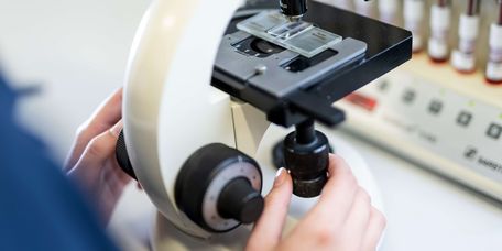 Medizinische Fachangestellte untersucht Proben unter dem Mikroskop