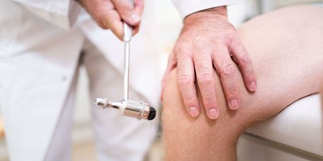 Arzt teste Knierelfexe mit einem kleinen Hammer